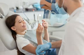 child holding up mirror in dentists office