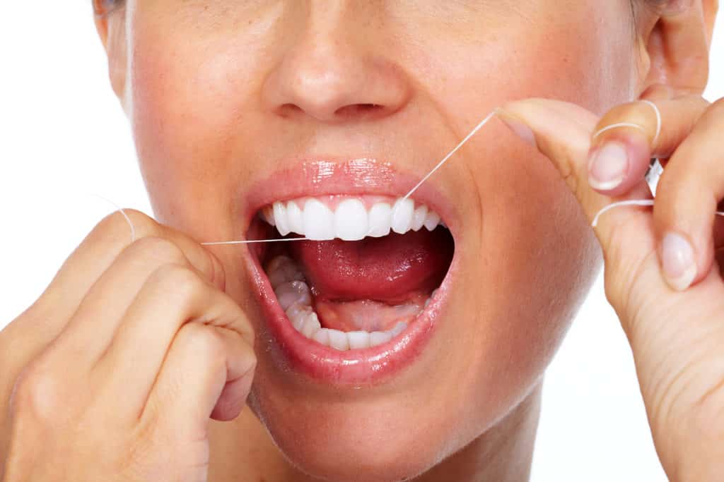 woman flossing her white teeth up close