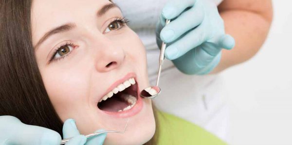 Dentist Examining Patients Teeth With Mouth Wide Open — Dentist In Gosford, NSW