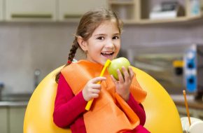 Little Girl Holding An Apple And Toothbrush