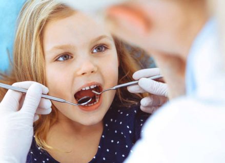 Little Girl Sitting At Dental Chair With Open Mouth — Dentist In Gosford, NSW