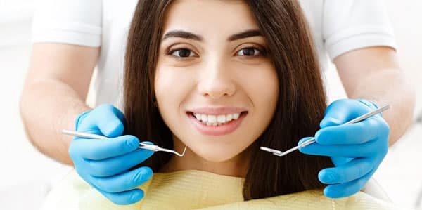 dentist holding up dental tools in front of woman