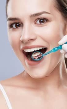 woman smiling with dentist holding up mirror