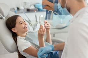 child holding up mirror in dentists office