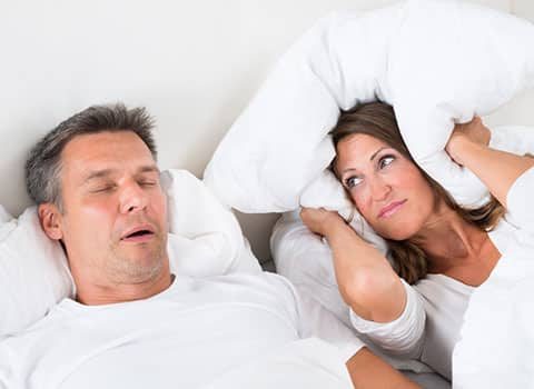 man snoring and wife glaring at him