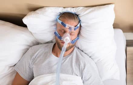 man sleeping with sleep apnoea mask