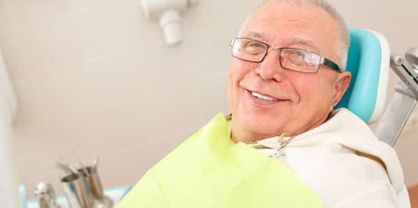 older man sitting in patient dental chair at dentist