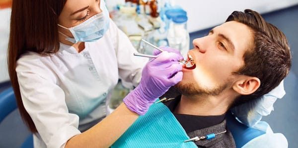 woman using mirror to perform check up on mans teeth