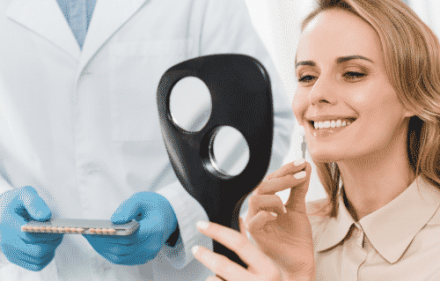 woman looking at dental implant in mirror at dentist